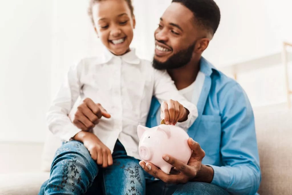 dad daughter put money in piggy bank.width .jpg