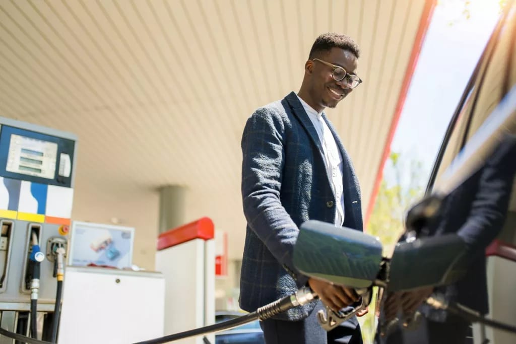 person filing up their car with gas AhVsk.width .jpg