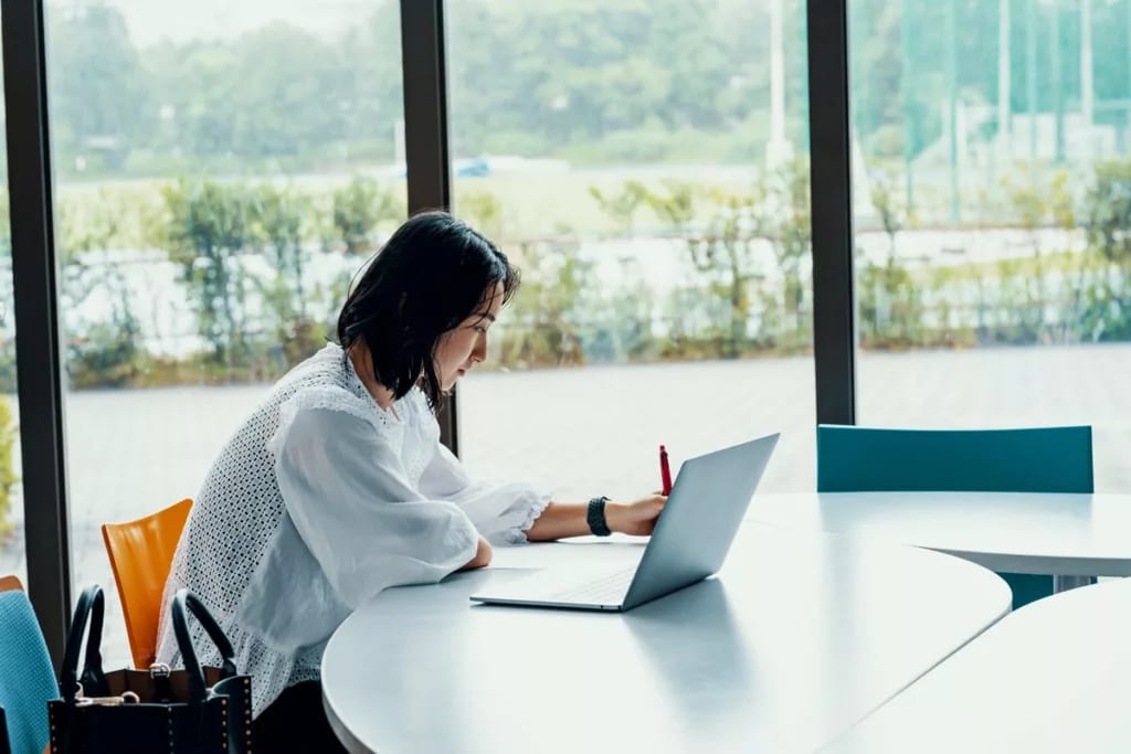 person writing at desk next to laptop DJgfk.width .jpg