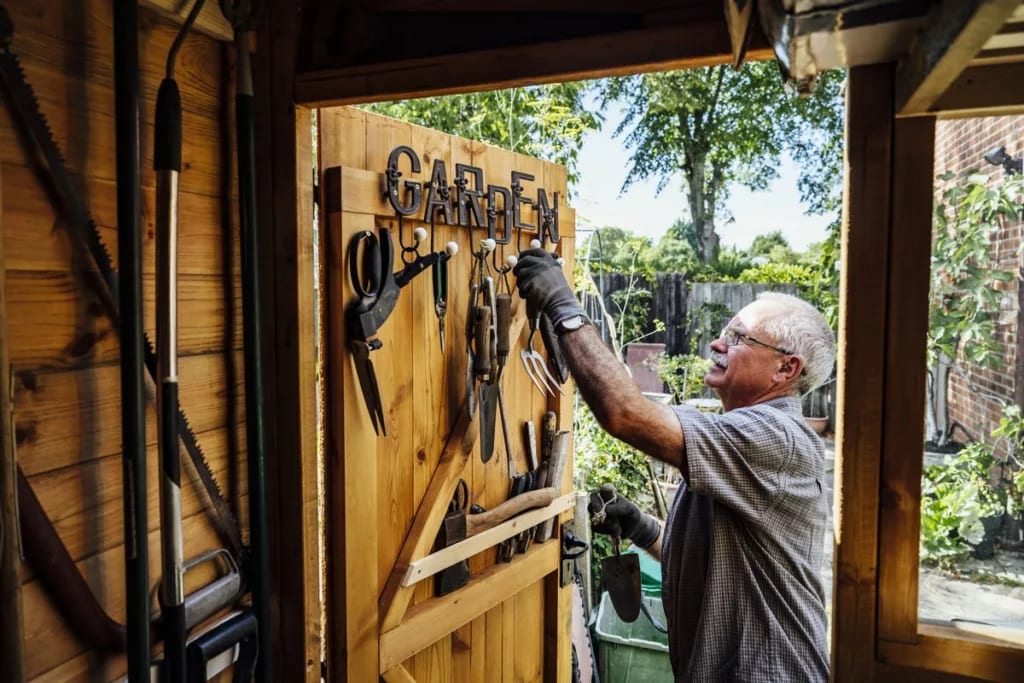Homeowner storing gardening tools in his shed.width .jpg