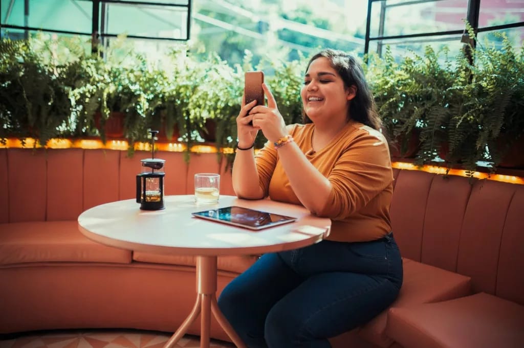person at coffee shop table with phone JvOTB.width .jpg