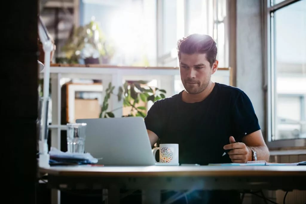 young man sitting at desk using laptop and th.width rNXRoV.jpg