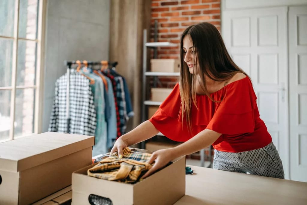 Woman boxing up some of her clothes. yDycw.width .jpg
