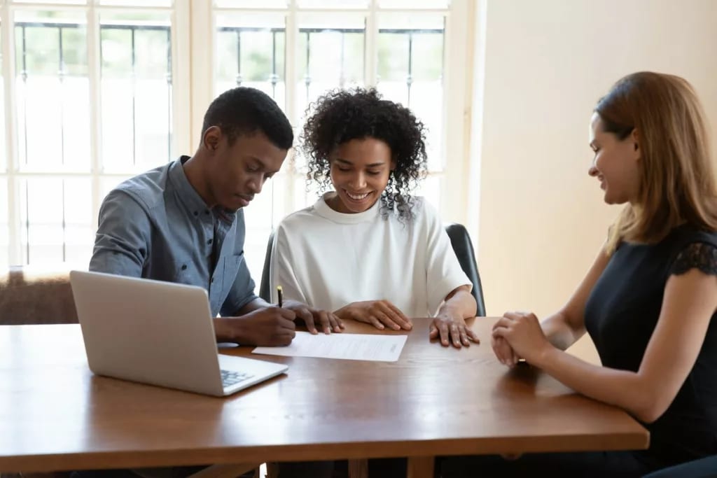 Young couple signing paperwork while a profes.width LTeaxO.jpg