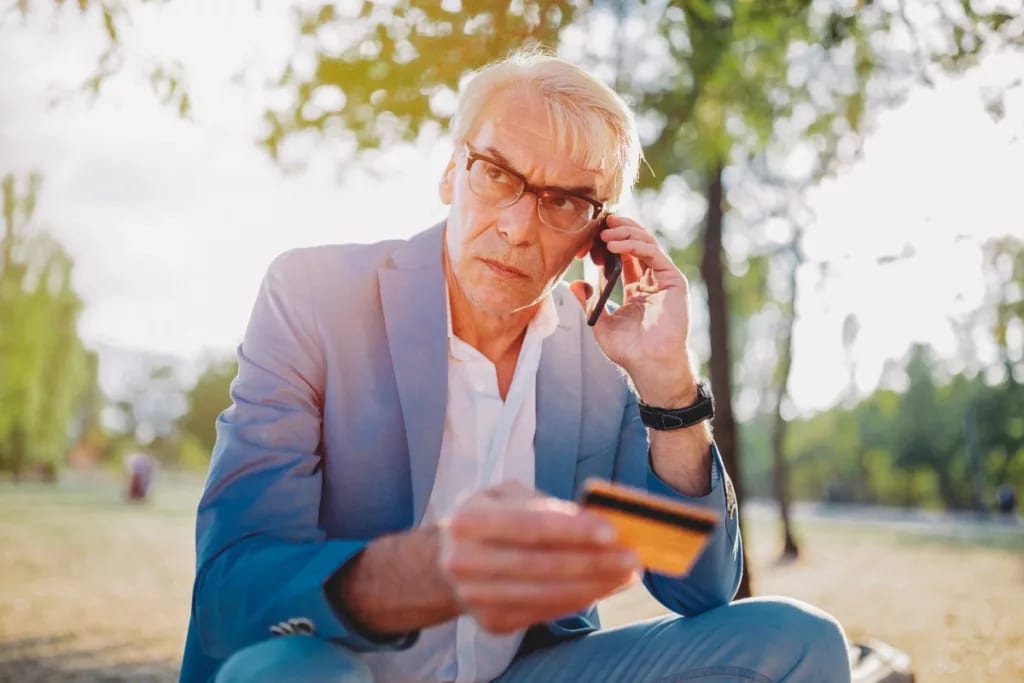 older man upset on phone holding credit card .width NRkzbw.jpg
