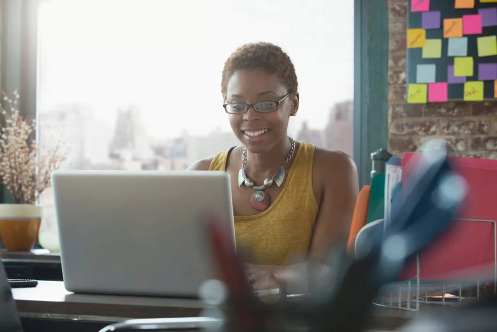 Woman smiling as she uses her laptop yKHtHfd.width .jpg