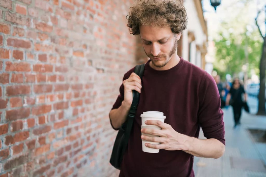 man s holding coffee to go gettyimages .jpg
