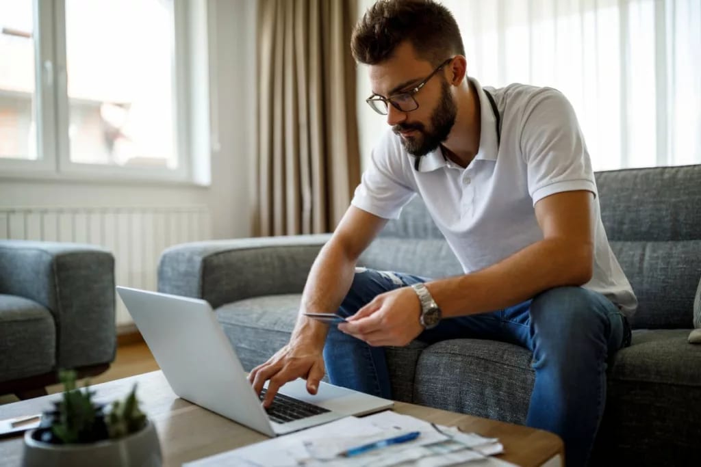person on couch with laptop and credit card .width .jpg