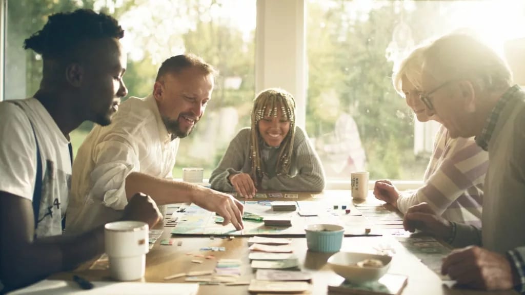 A group of adults playing a board game at a t.width .jpg