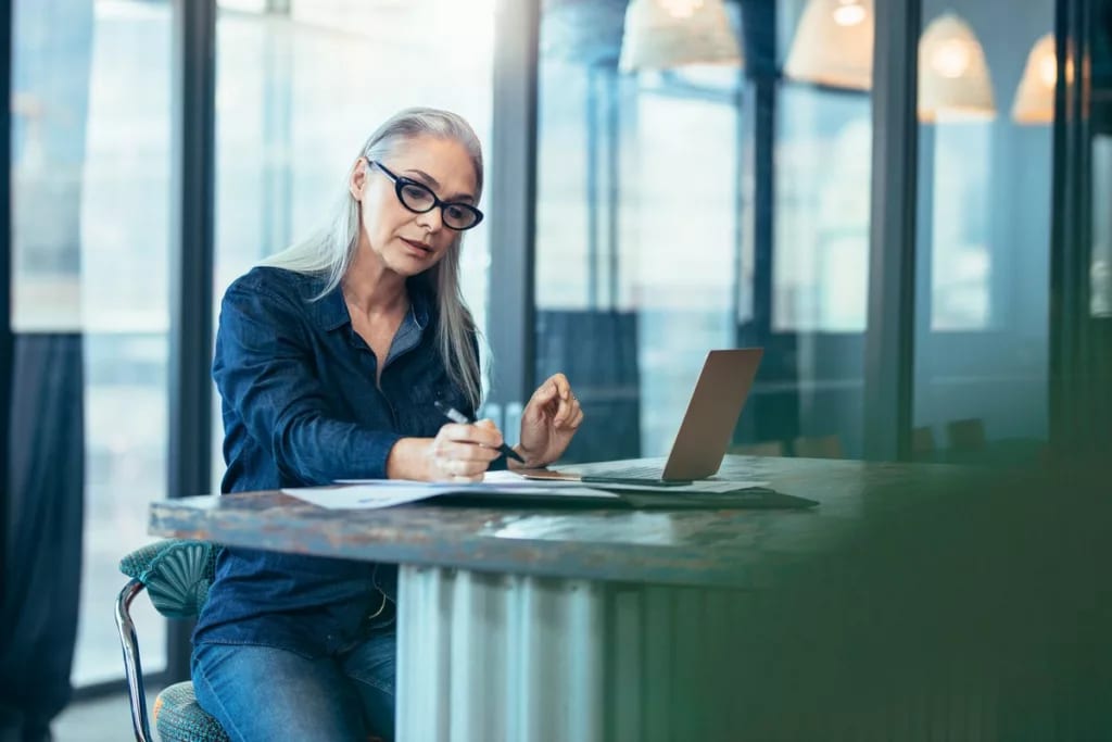 Woman reading paperwork at a desk FZuNqt.width .jpg