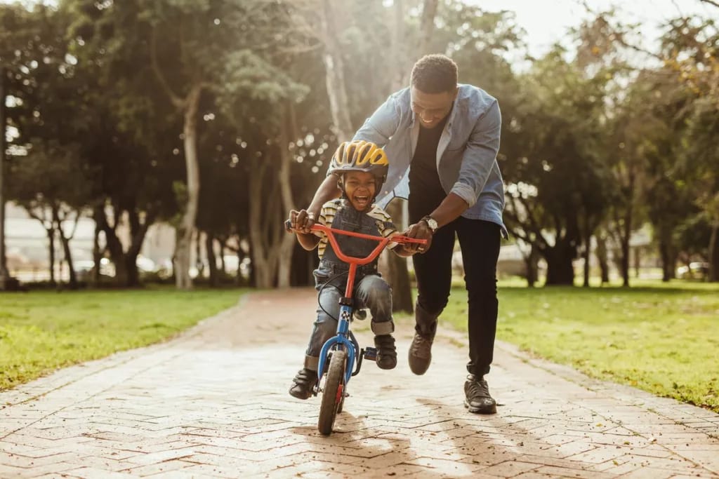 Dad helping young son ride bike RZUCj.width .jpg