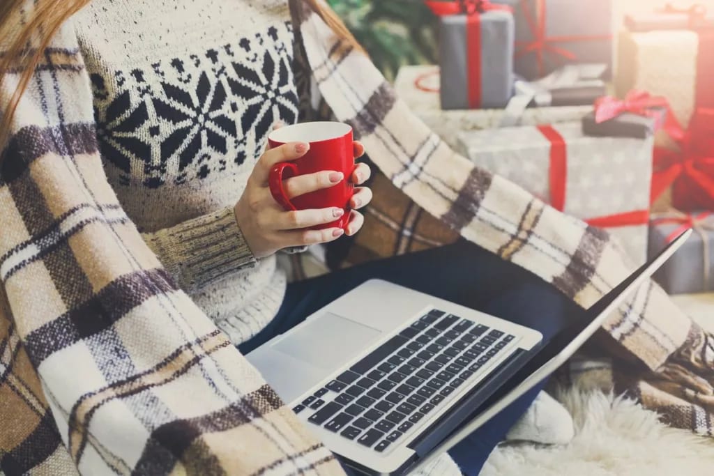 Woman on laptop with blanket and presents RZZ.width .jpg