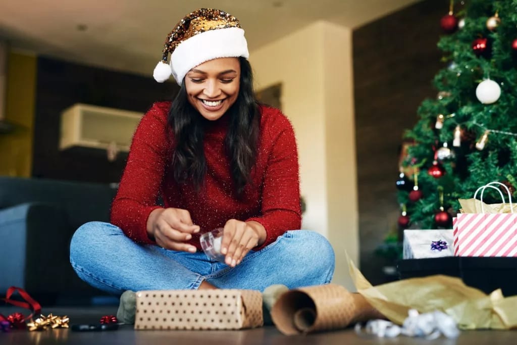 Woman wearing Santa hat wrapping gifts RKFz.width .jpg