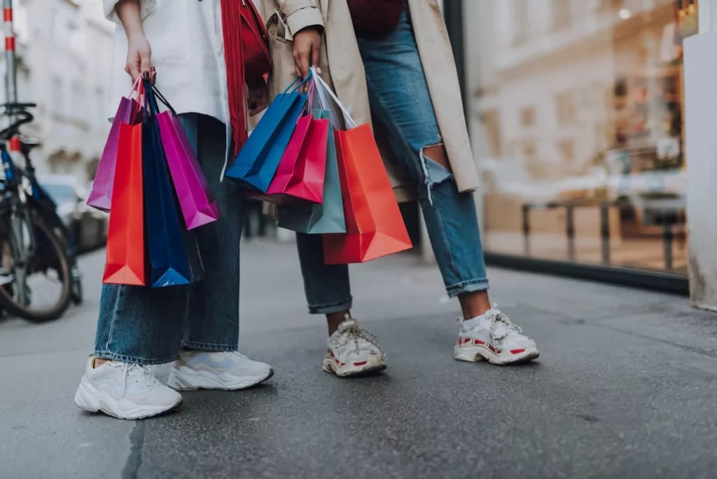 two women holding shopping bags on street.width .jpg