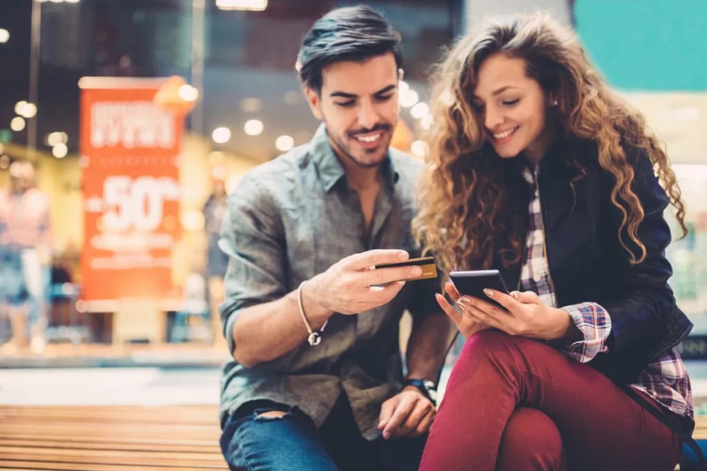 young couple at mall with phone and credit ca.width .jpg