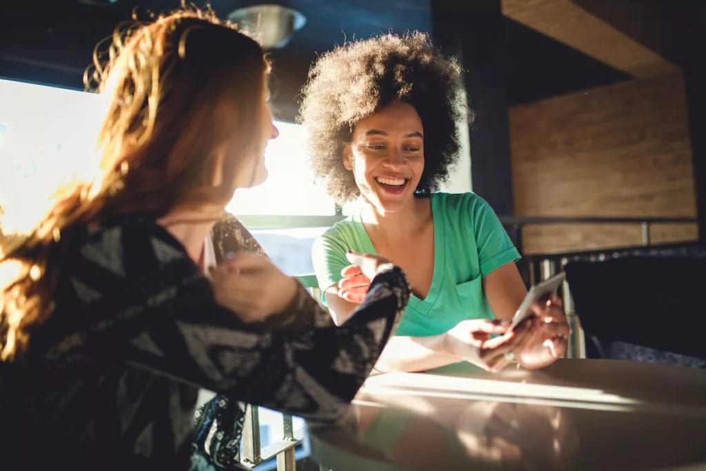 Friends looking at the mobile phone at a cafe.width qMyFab.jpg