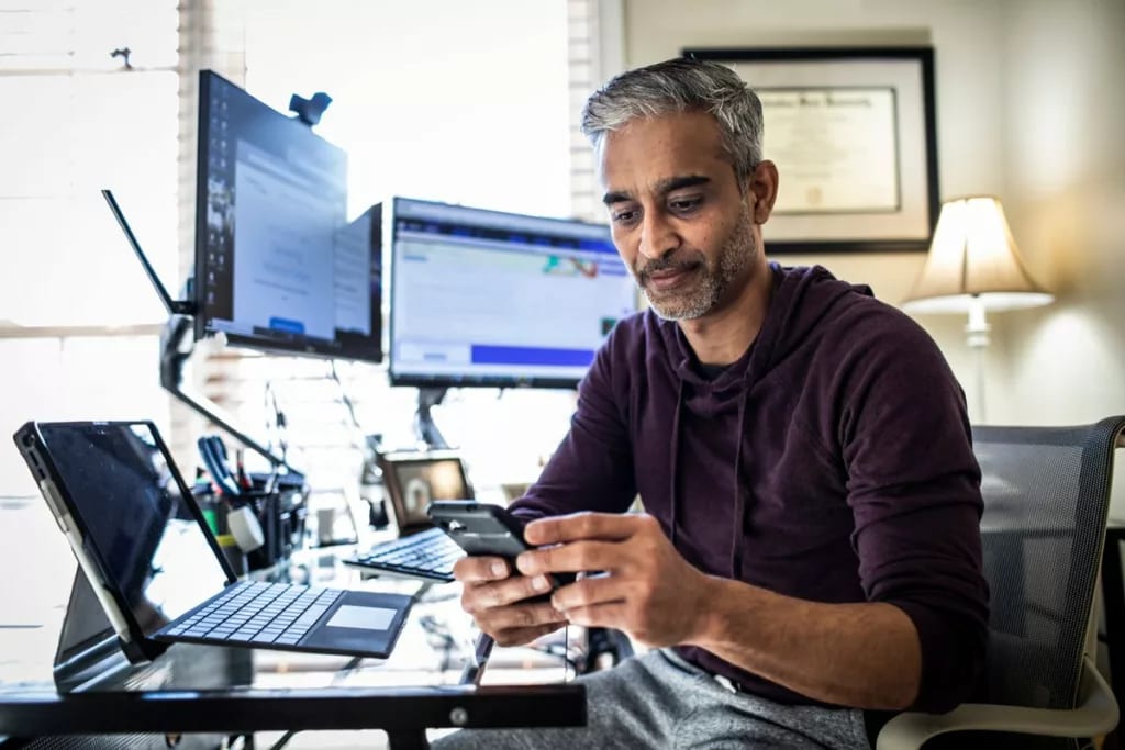 Man using is cell phone while sitting at desk.width zOrjm.jpg