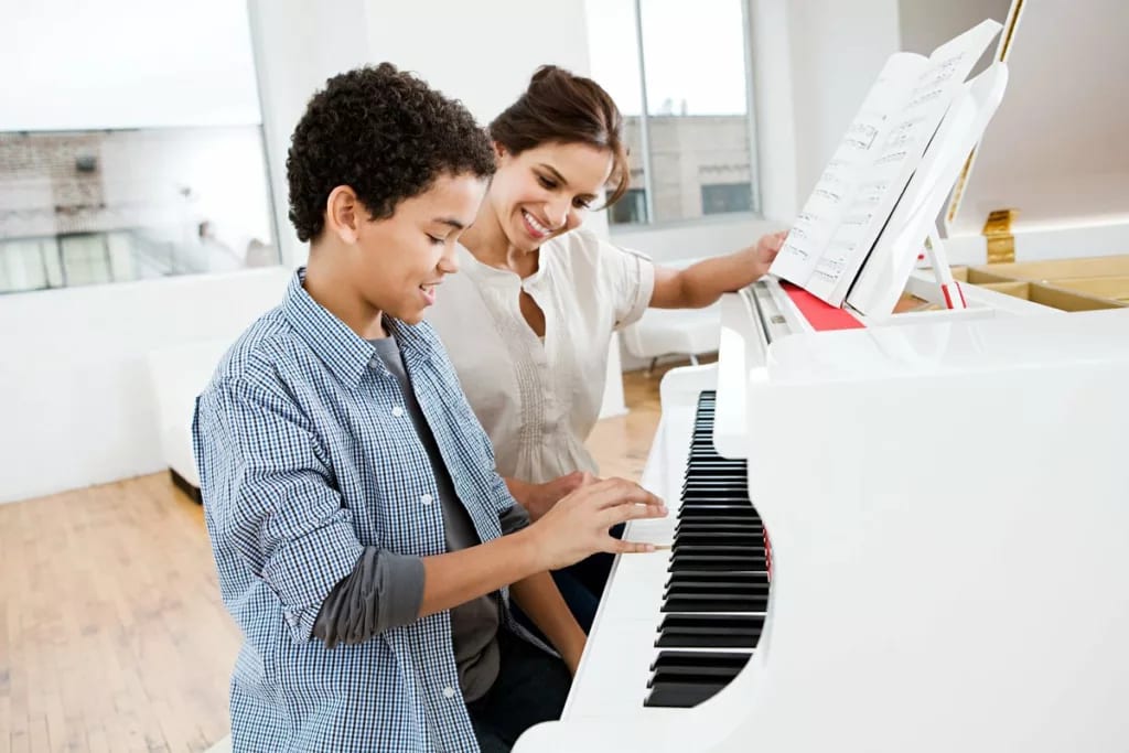 Woman giving young boy piano lessons lHvgOq.width .jpg