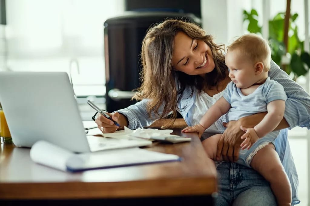 Woman working on taxes while holding infant i.width GkqVTs.jpg