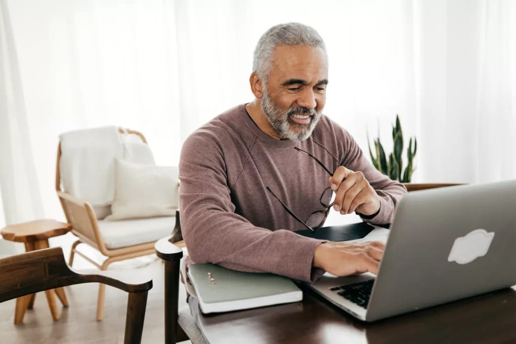 smiling person holding glasses and looking at laptop.jpg