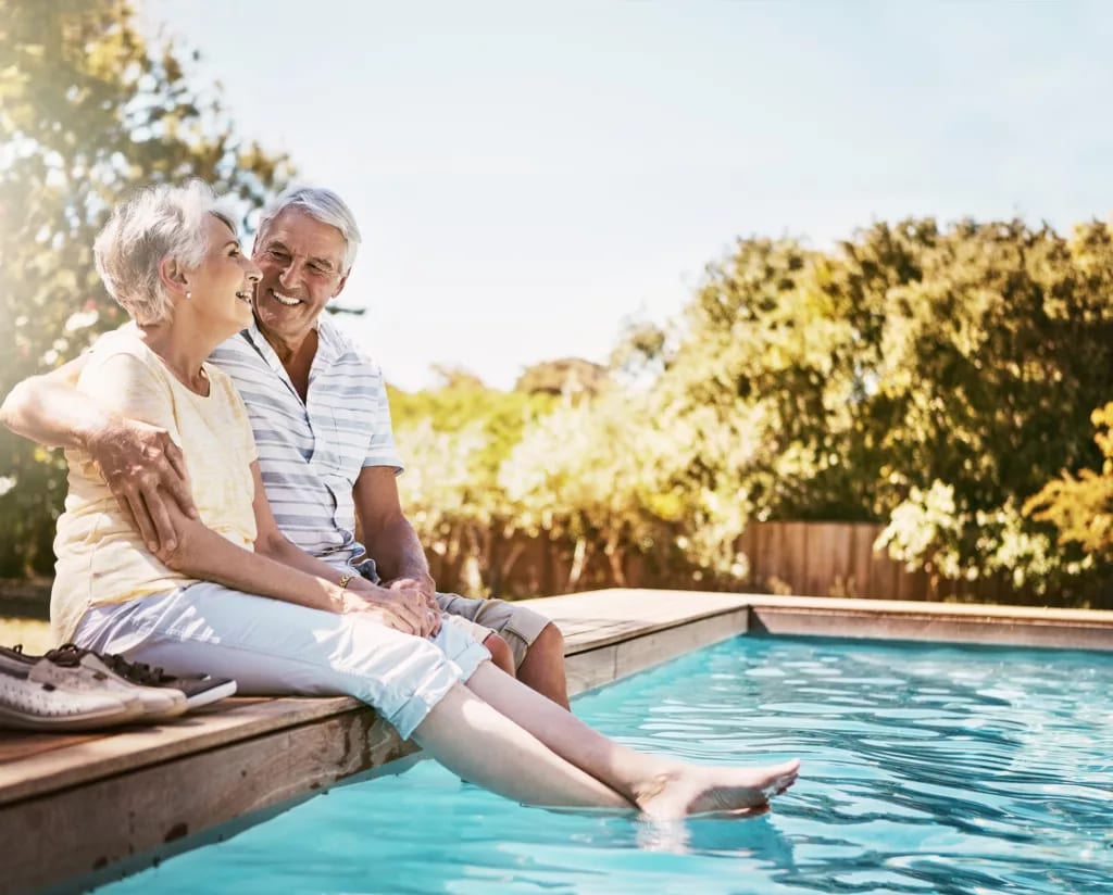 smiling seniors sitting by a pool.jpg