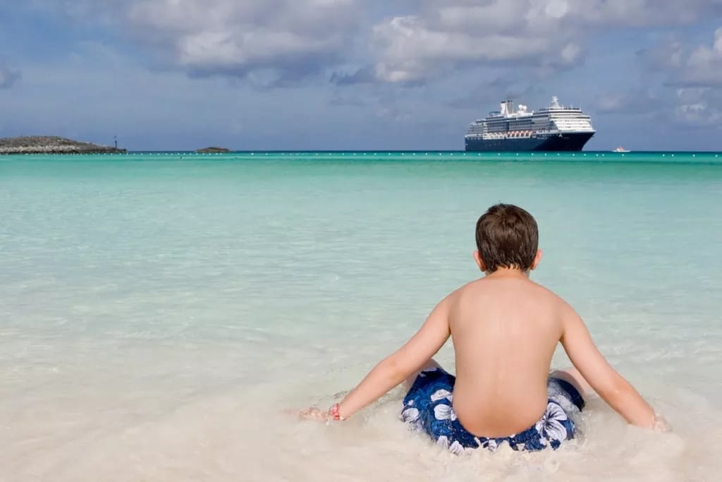 Child on shore of beach with cruise ship off .width .jpg