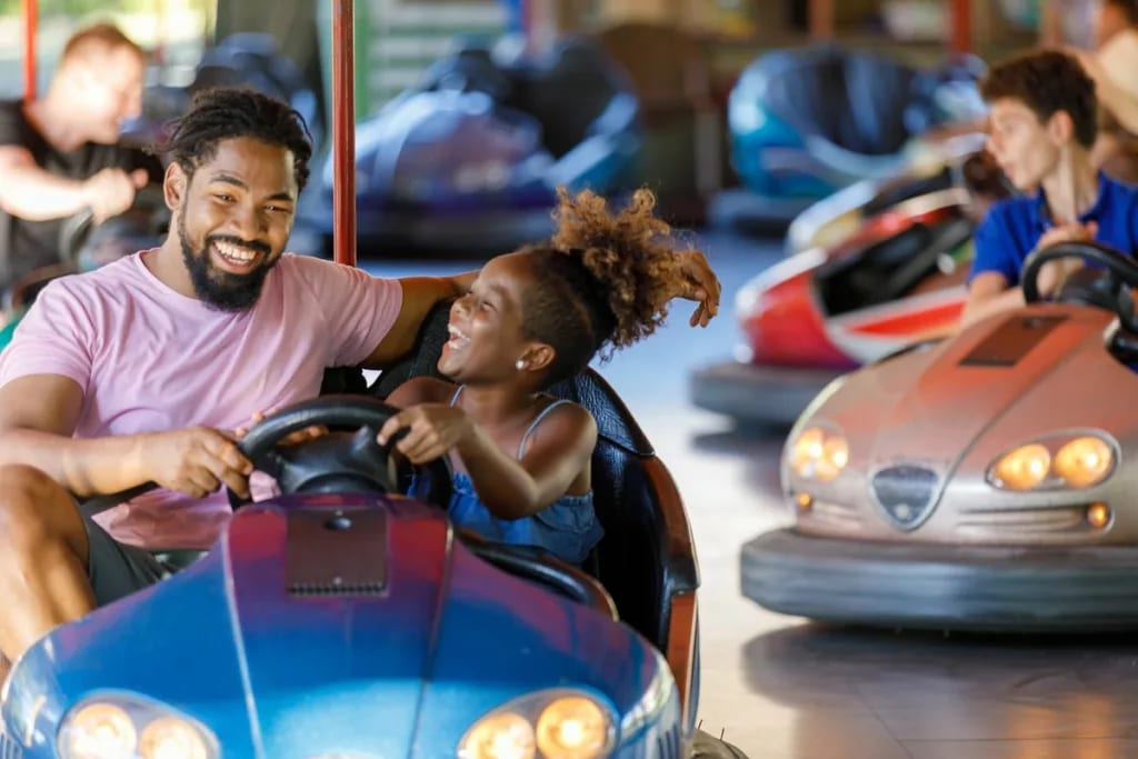 Smiling adult and child riding bumper cars at.width .jpg