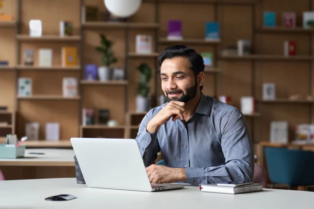 person sitting at a desk looking at a laptop and smiling.jpg