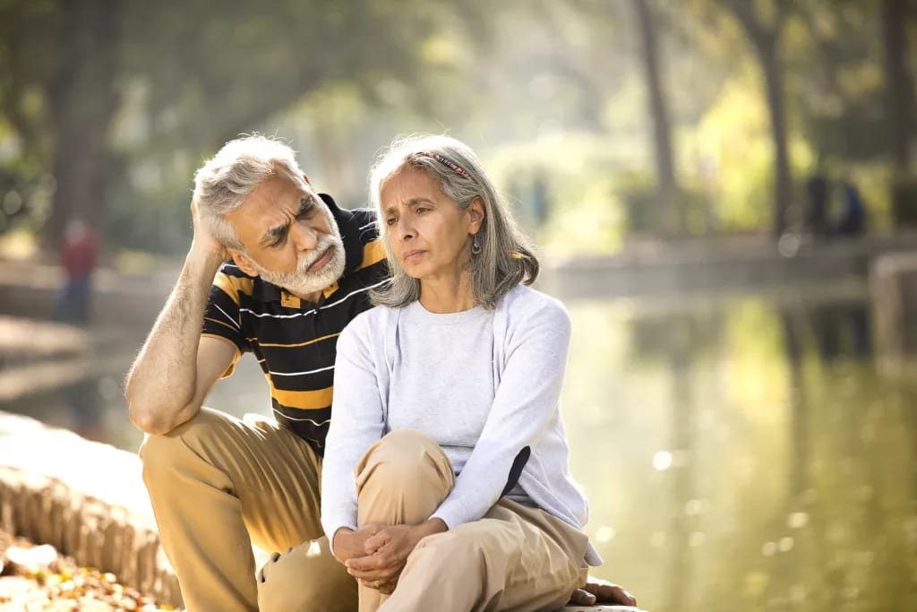 two older people sitting outside looking serious.jpg