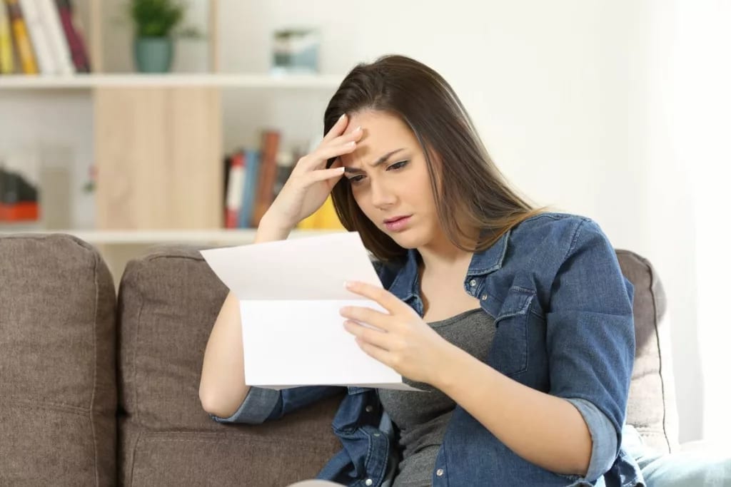 woman reading document while holding her head.width feNYQG.jpg