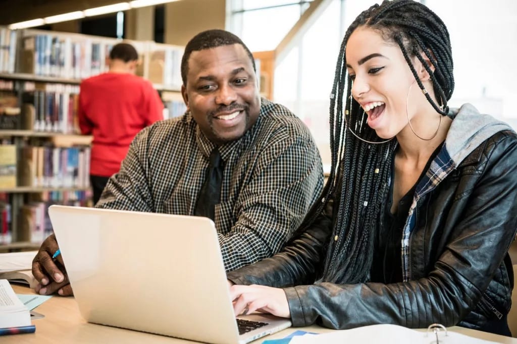 Young woman smiling using laptop next to adul.width WmlZso.jpg