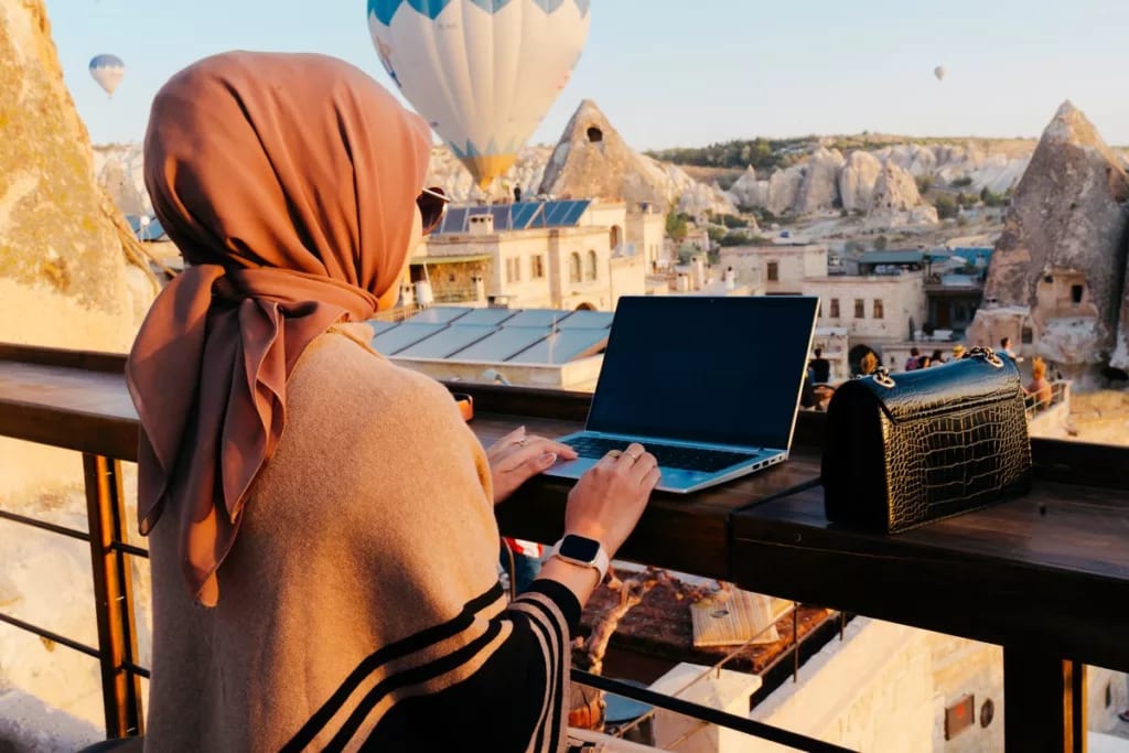 person with laptop on balcony and hot air bal.width .jpg