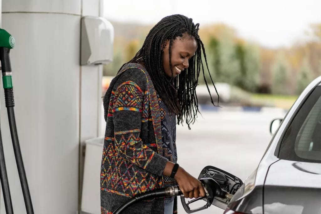 Person smiling while pumping fuel into vehicl.width .jpg