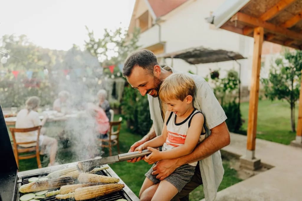 Father and son grill corn during a cookout on.width .jpg