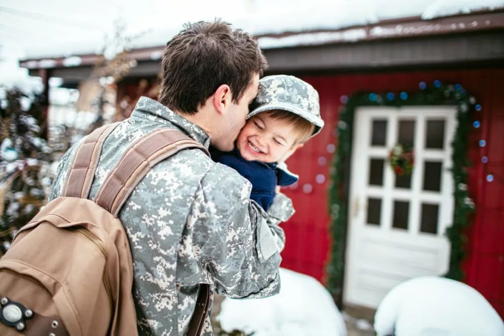Military father with backpack hugging child o.width CYIFza.jpg