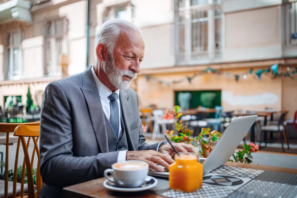 senior businessperson typing on laptop at coffee shop.jpg
