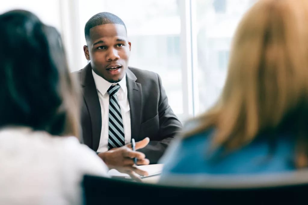 suited businessperson talking to two clients.jpg