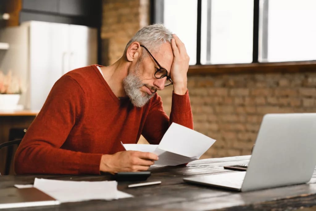 older man stressed holding document at laptop gettyimages .jpg