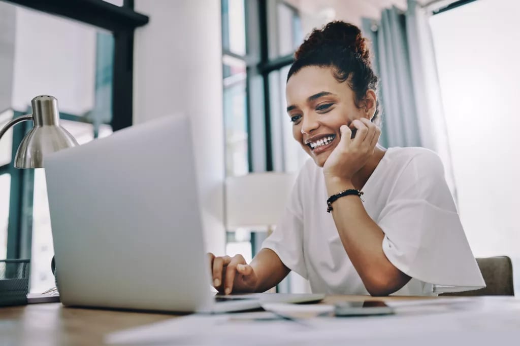 smiling young person with hand on chin looking at laptop.jpg