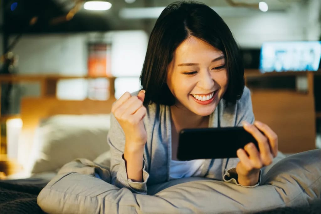 excited person lying on bed looking at phone screen.jpg