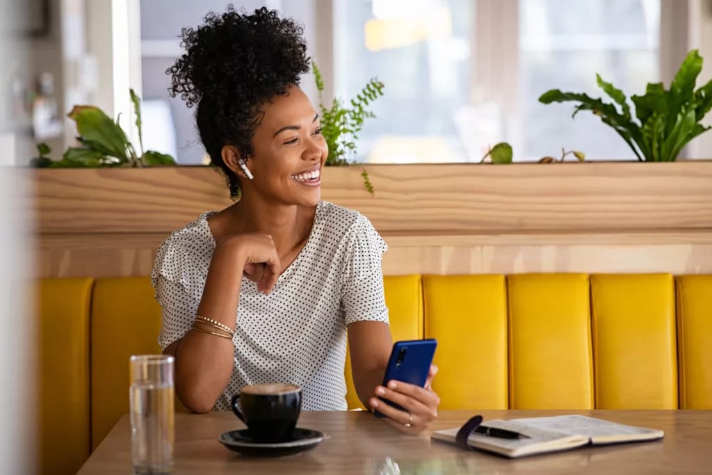 smiling person holding phone sitting in coffee shop.jpg