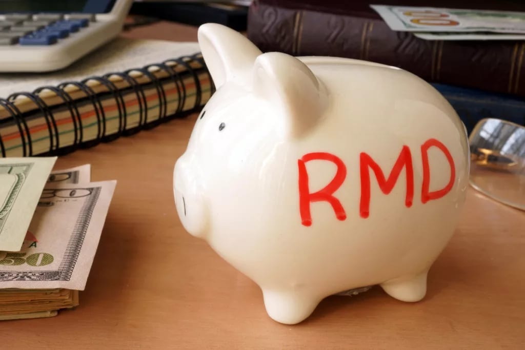 getty images piggy bank with rmd written on its side next to stack of paper money retirement savings k ira cash x bdf.jpg