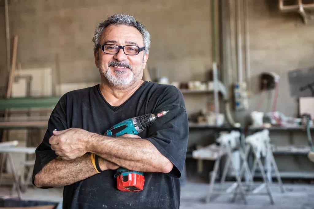 getty smiling happy workers with tool drill blue collar.jpg
