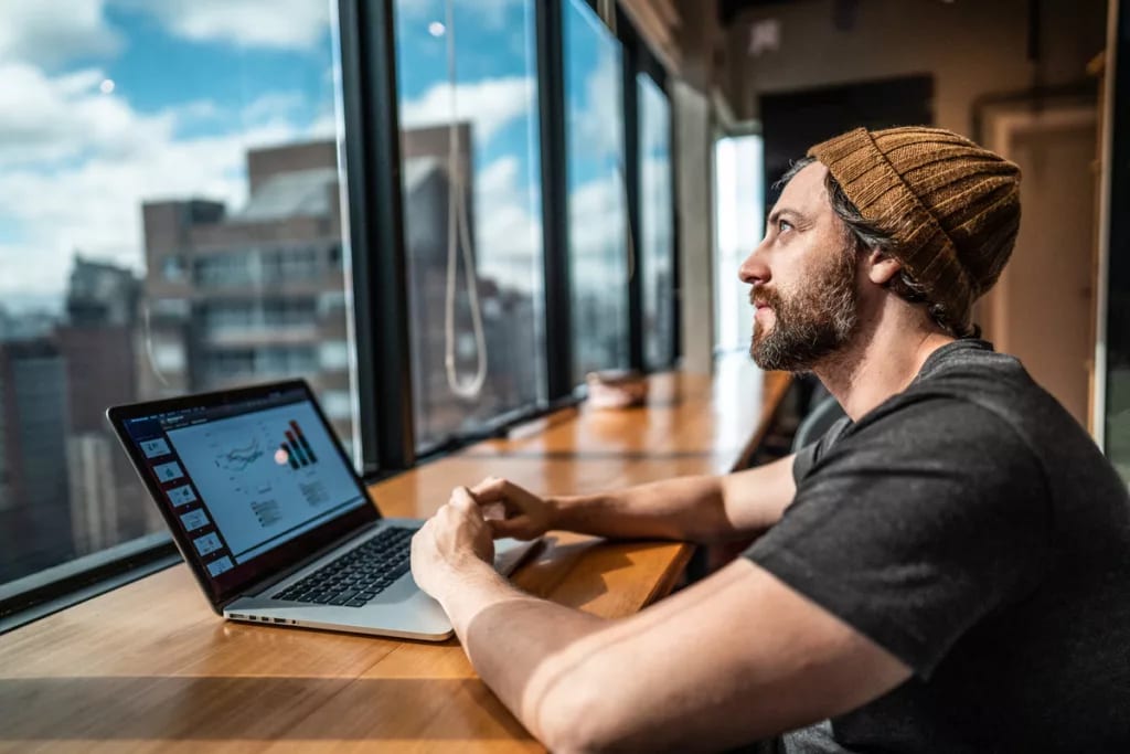 person sitting in front of laptop looking out window of office building.jpg