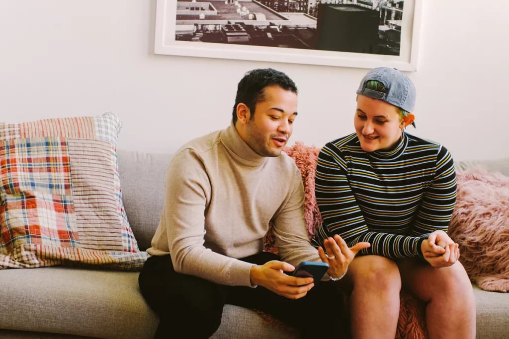 smiling couple discussing something on smartphone.jpg