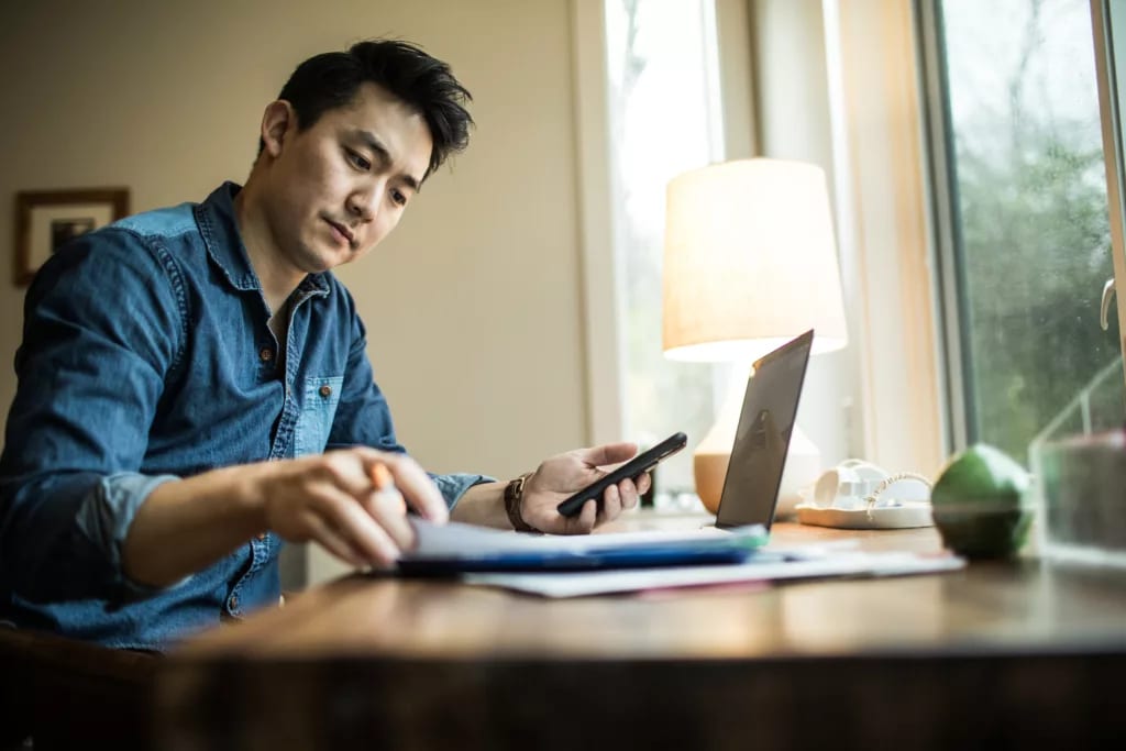 person in home office holding smartphone and looking at document.jpg