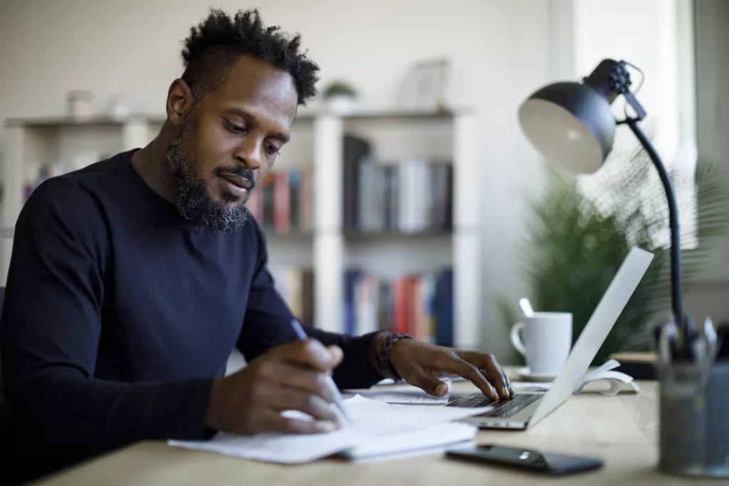 person sitting at a desk looking at a laptop and documents.jpg