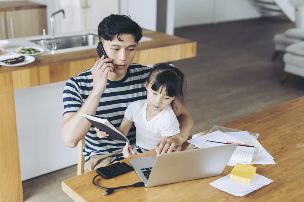 person talking on phone and looking at laptop with child on lap.jpg