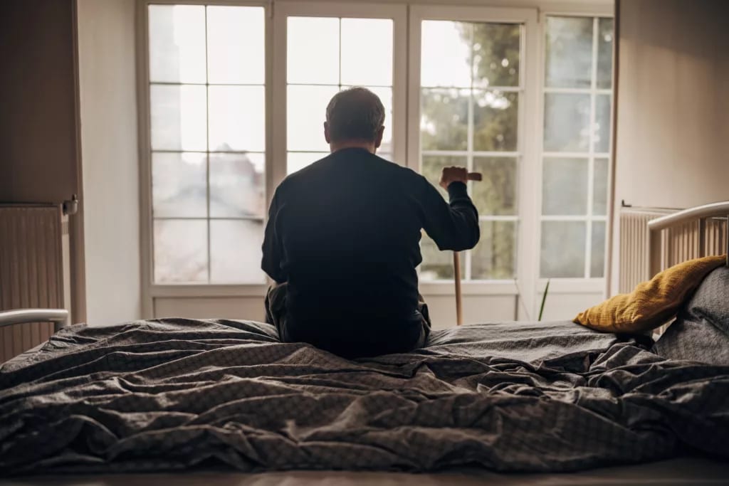 retired man with cane sitting on bed.jpg
