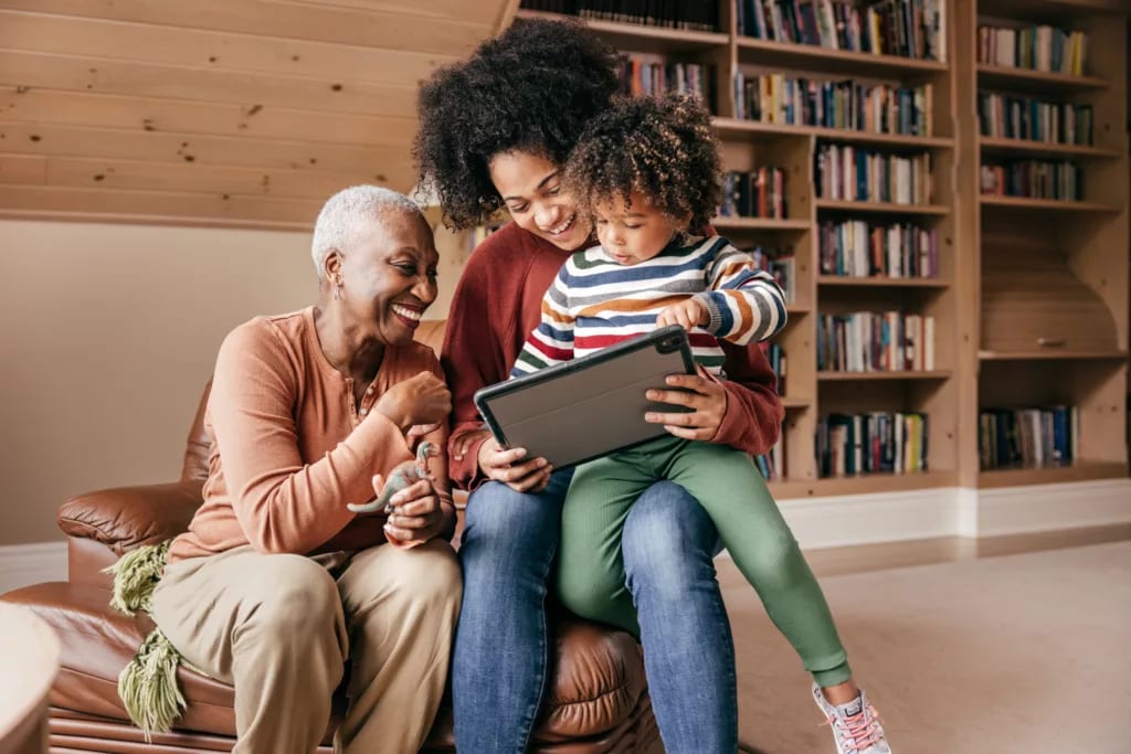 two adults and a child looking at a tablet and smiling.jpg